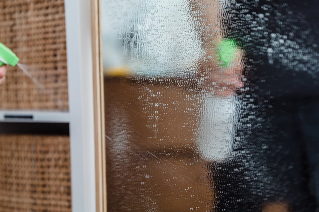 Detailed view of a mirror being cleaned using a water sprayer, indoors.